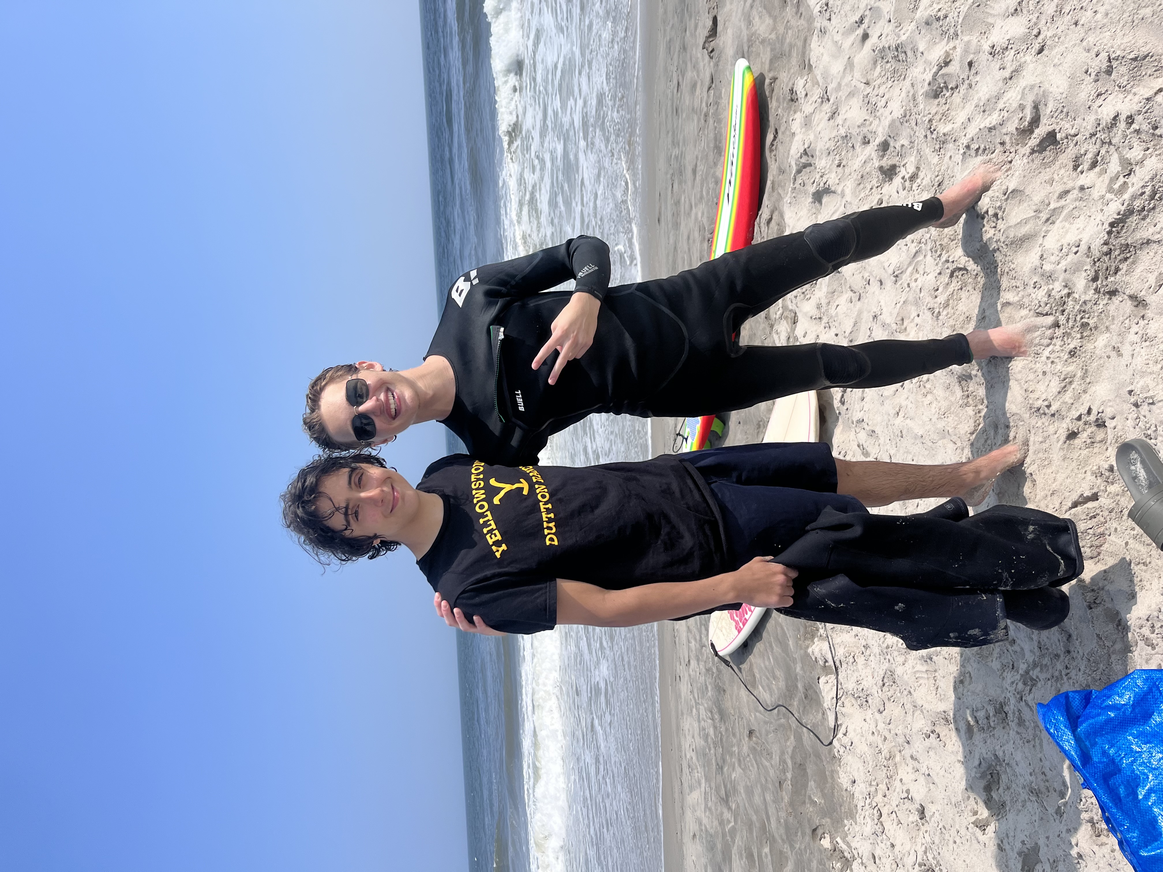 Two surf students smiling on the beach after a great lesson