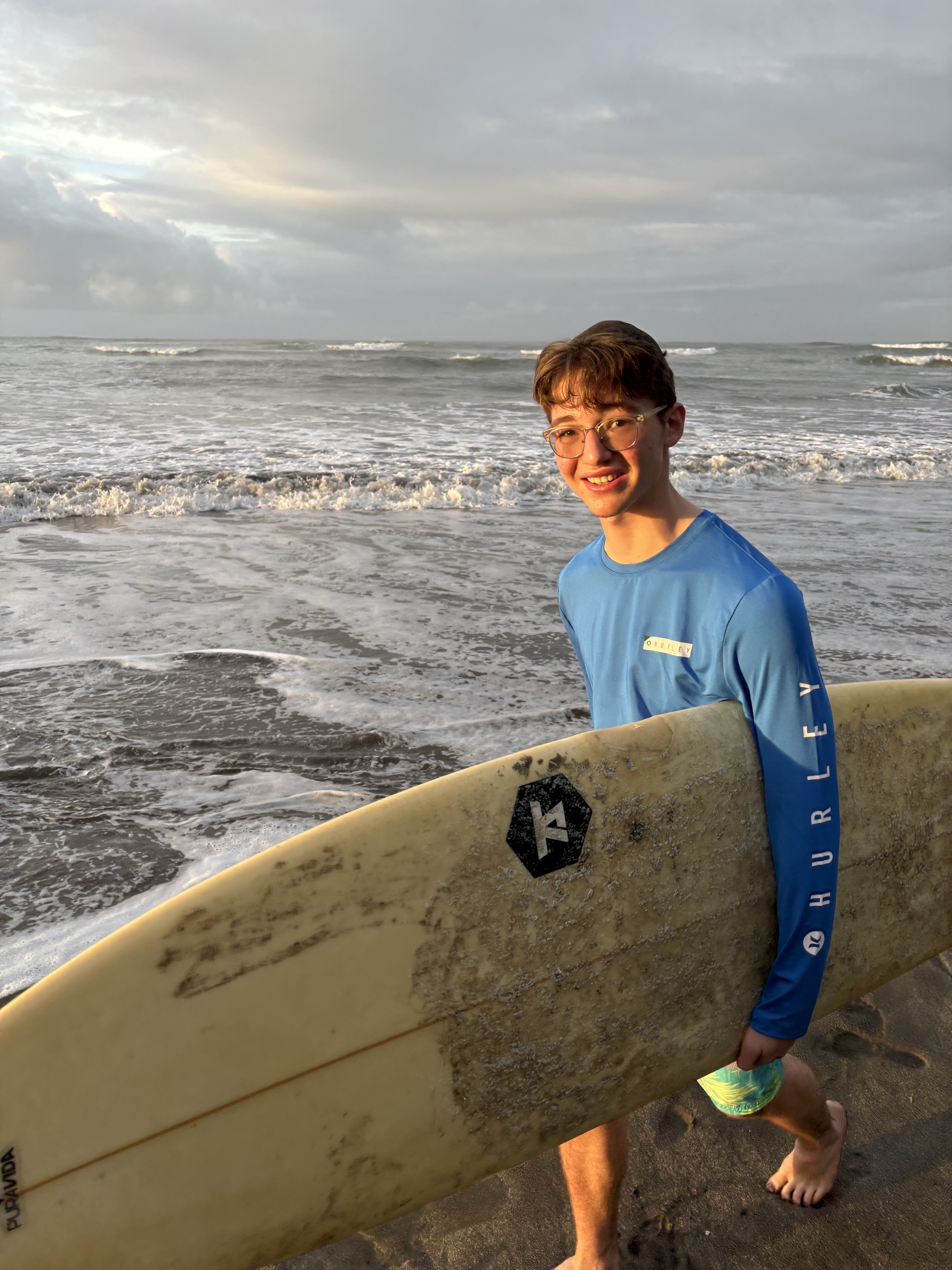 Lesson students posing with a surfboard at the beach